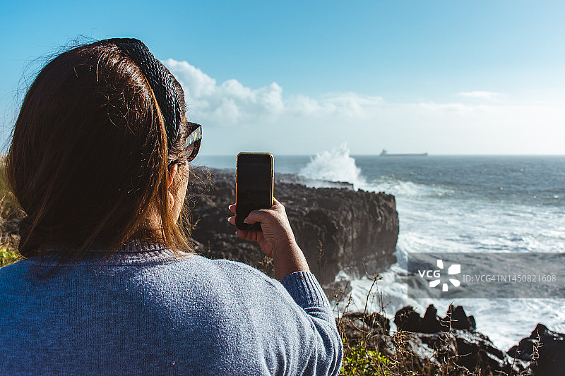 女子拍摄海浪的背影图片素材