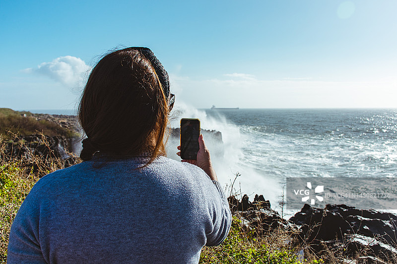 女子拍摄海浪的背影图片素材