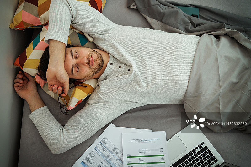 疲惫的年轻男人，在家工作时在卧室睡觉图片素材