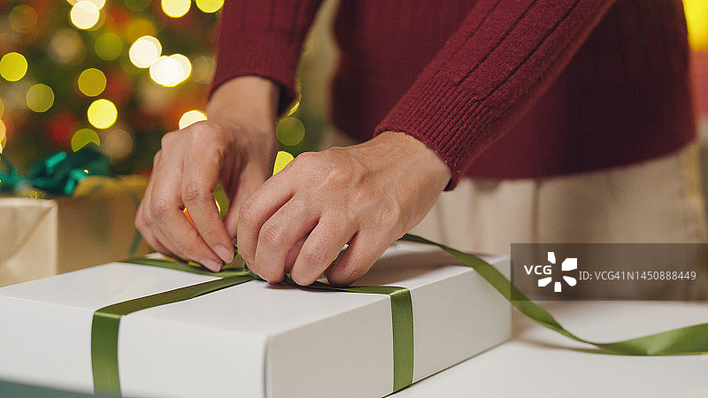 年轻的亚洲女人在客厅的桌子上打开圣诞礼物图片素材