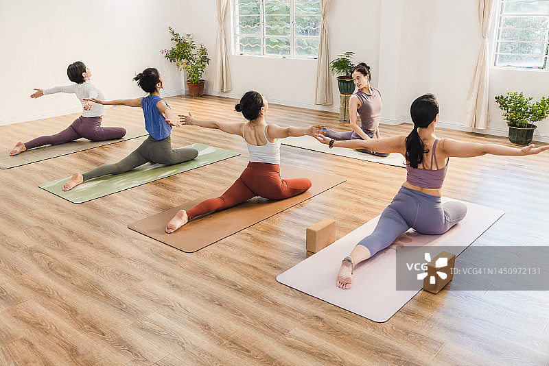 亚洲女性在瑜伽馆与教练一起上瑜伽课图片素材