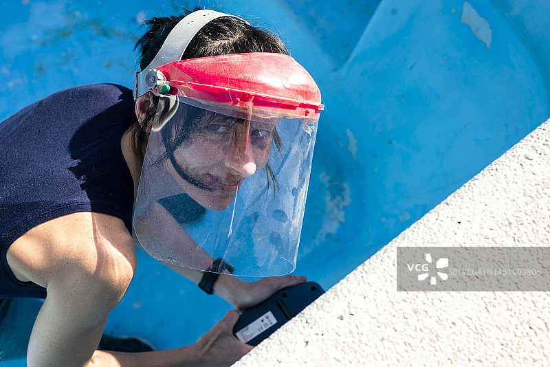 戴防护口罩用打磨机打磨游泳池墙壁的女人图片素材