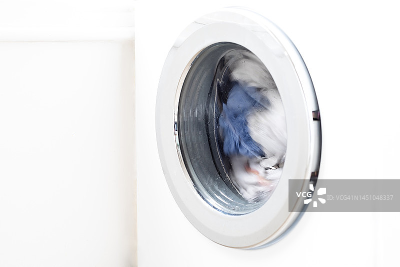 白色洗衣机和浅色衣物特写图片素材