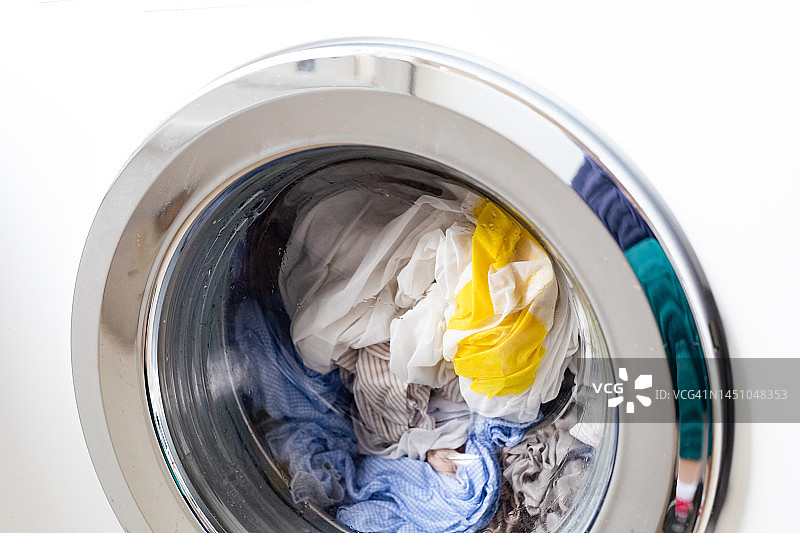 白色洗衣机和浅色衣物特写图片素材