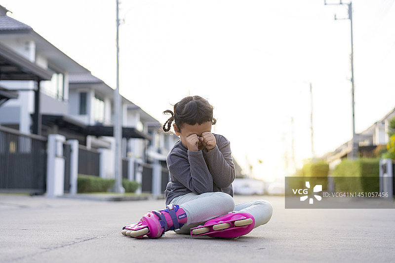 亚洲小女孩玩轮滑摔倒，未佩戴护具受伤图片素材