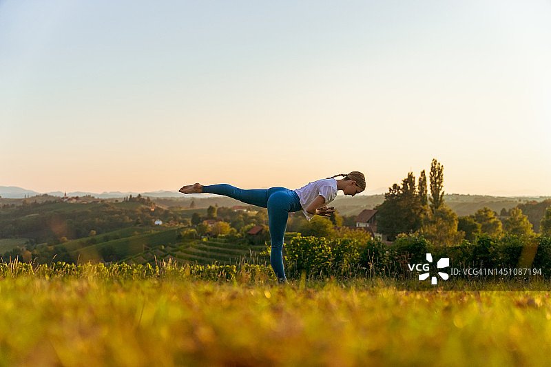 日出时在风景中练习战士三式瑜伽的女人图片素材