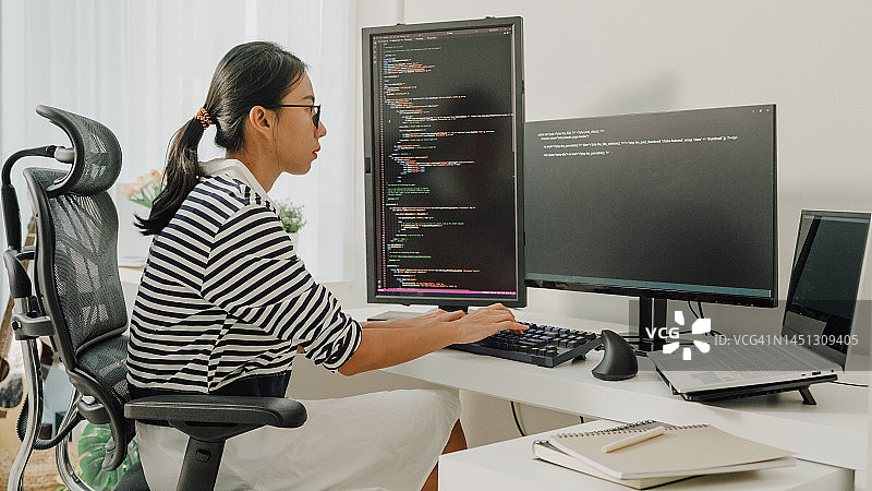 年轻亚洲女性软件开发人员在家远程工作，用电脑编写代码图片素材