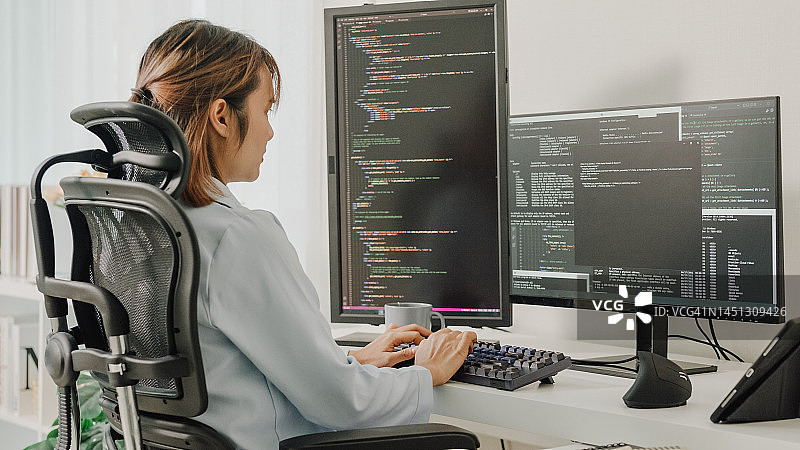 年轻亚洲女性软件开发人员在家远程工作，用电脑编写代码图片素材
