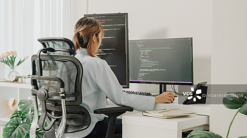 年轻亚洲女性软件开发人员在家远程工作，用电脑编写代码图片素材