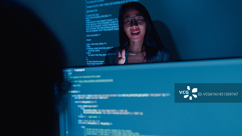 年轻的亚洲女软件开发人员指导团队，与高管团队交谈，分析办公室夜间的源代码图片素材