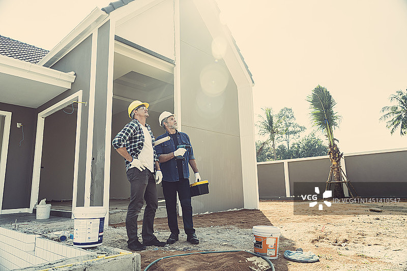 工人、承包商、工程师身穿格子衬衫，头戴黄色安全帽，携带工具箱。在正在建造、翻新、改造的房屋内，专业技术人员准备按照需求维修、改进和建造房屋图片素材