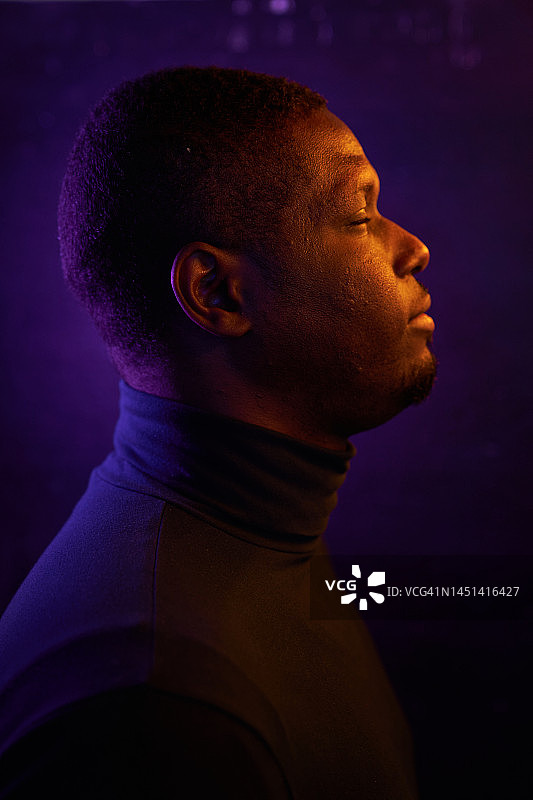 一位年轻的非裔美国男士的侧面轮廓，身着未来主义时尚霓虹灯，闭着眼睛，留有复制空间。未来、梦想、现代科技、技术进步、逃避现实、心理健康的概念。图片素材