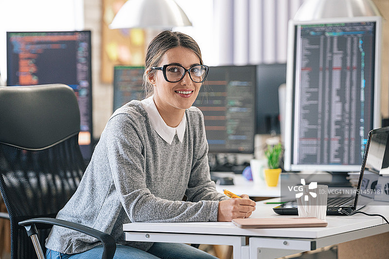 年轻女程序员在办公桌前编程的肖像图片素材