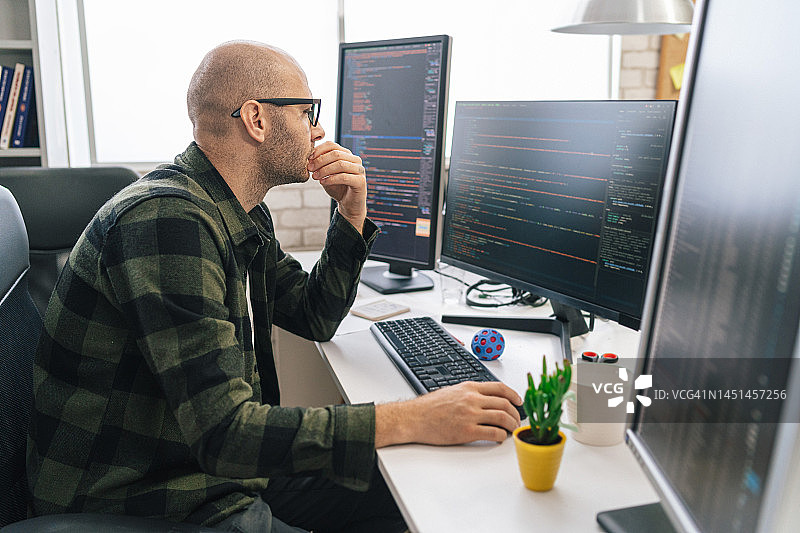 秃头IT程序员在台式电脑上工作。男性专家创建创新软件。工程师开发应用程序、程序、视频游戏。在终端编写代码图片素材