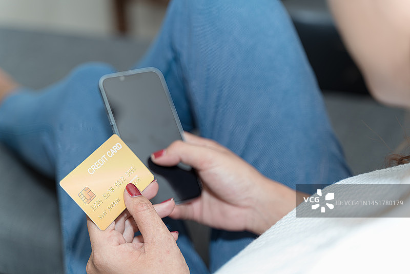 安全的手机银行。拉丁裔女士客户使用手机信用卡进行网上购物和支付。图片素材