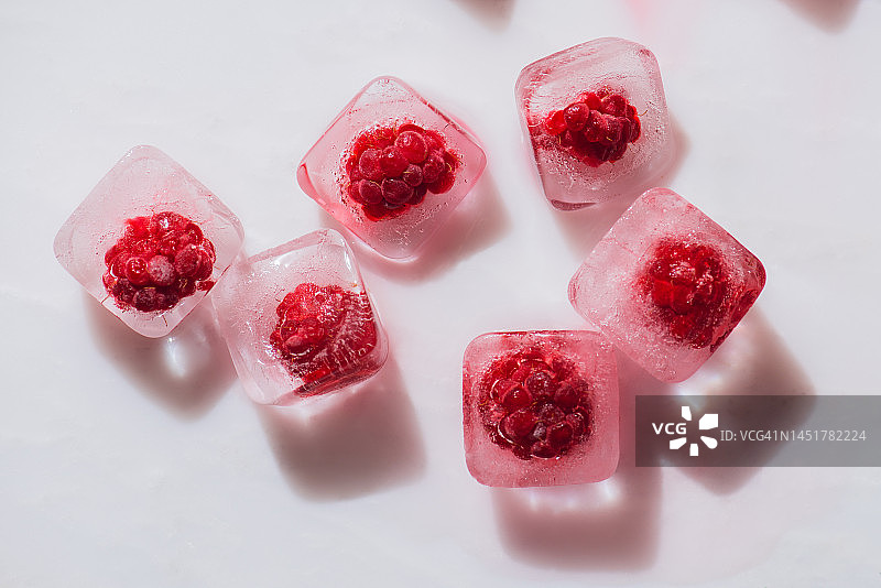 大理石表面冷冻冰块中的红色覆盆子，生鲜水果背景图片素材