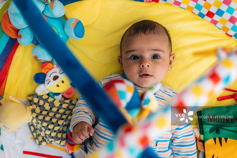可爱宝宝躺在黄色游戏毯上图片素材