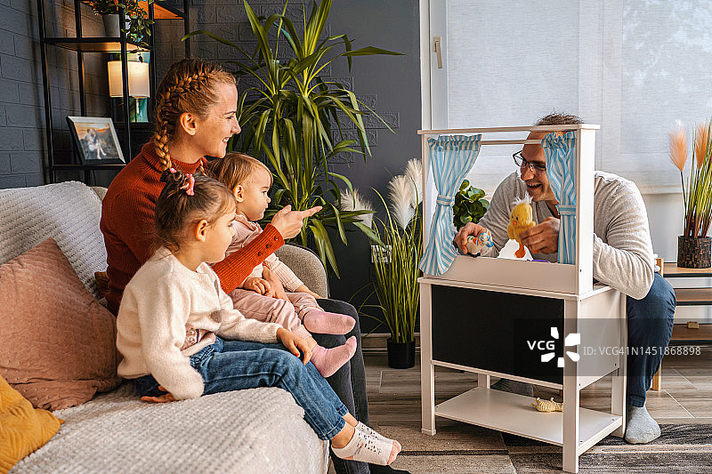 两个小女孩和她们的母亲在家欣赏木偶戏图片素材