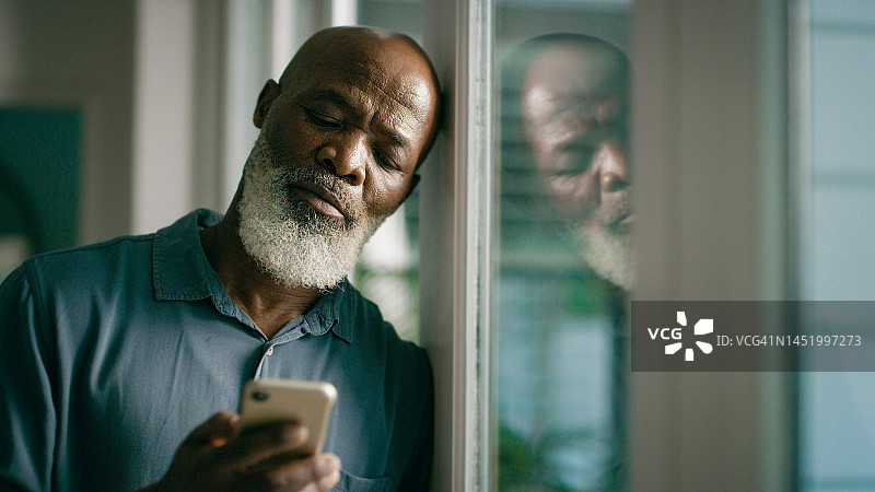 悲伤的黑人老年男人在手机上发短信，倾诉或输入社交网络信息。沮丧、抑郁和焦虑的孤独成熟人士或阅读后悔的短信图片素材