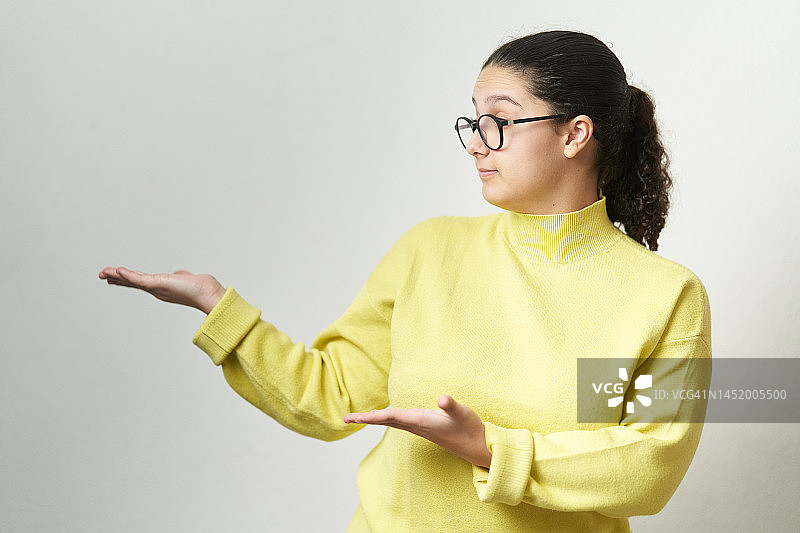 年轻女人站在孤立的背景上，展示她身边的东西图片素材