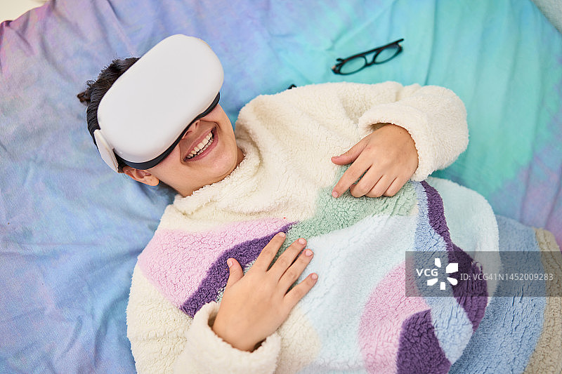 年轻女人躺在床上使用VR眼镜图片素材