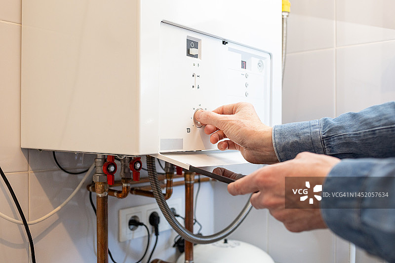 由于能源危机，白人男子降低家中燃气锅炉的温度图片素材