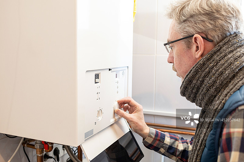 50岁男人因能源危机降低家中燃气锅炉温度图片素材