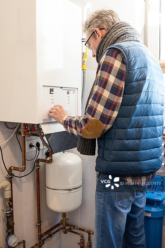 50岁男人因能源危机降低家中燃气锅炉温度图片素材