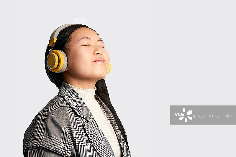 宁静的亚洲女人闭着眼睛听音乐图片素材