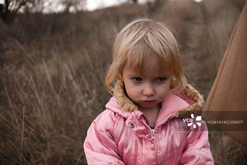 一个沮丧和委屈的小孩站在一个成年人旁边图片素材