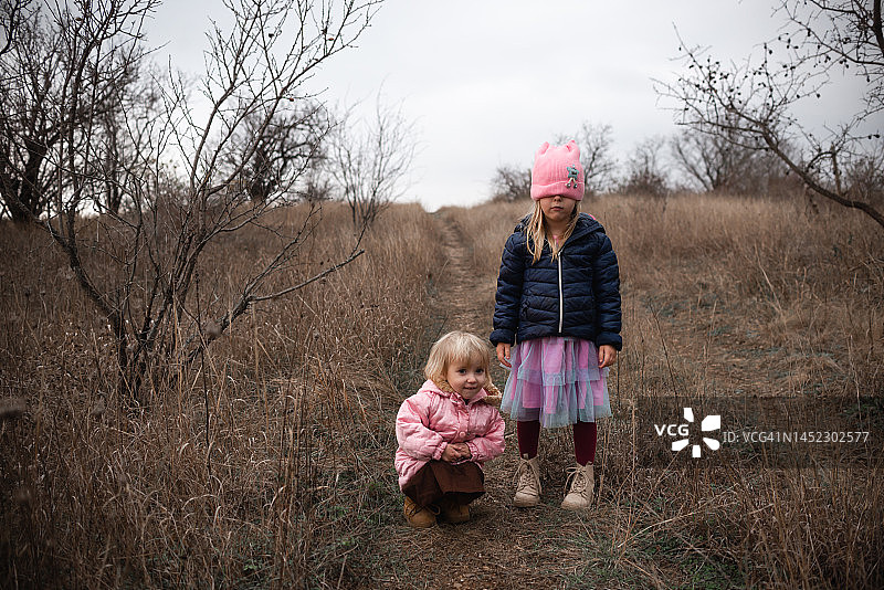 寒冷季节，姐妹俩站在公园小路上图片素材
