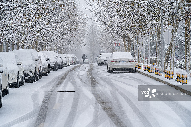 暴风雪中的男人，城市街道被厚厚的积雪覆盖图片素材
