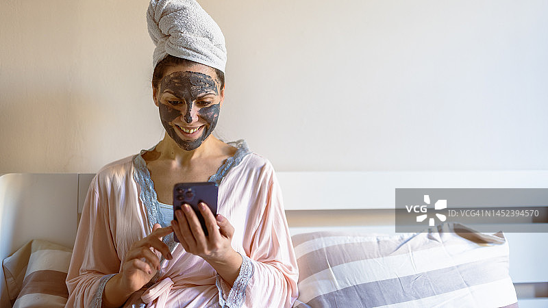 女人在卧室里使用手机App图片素材