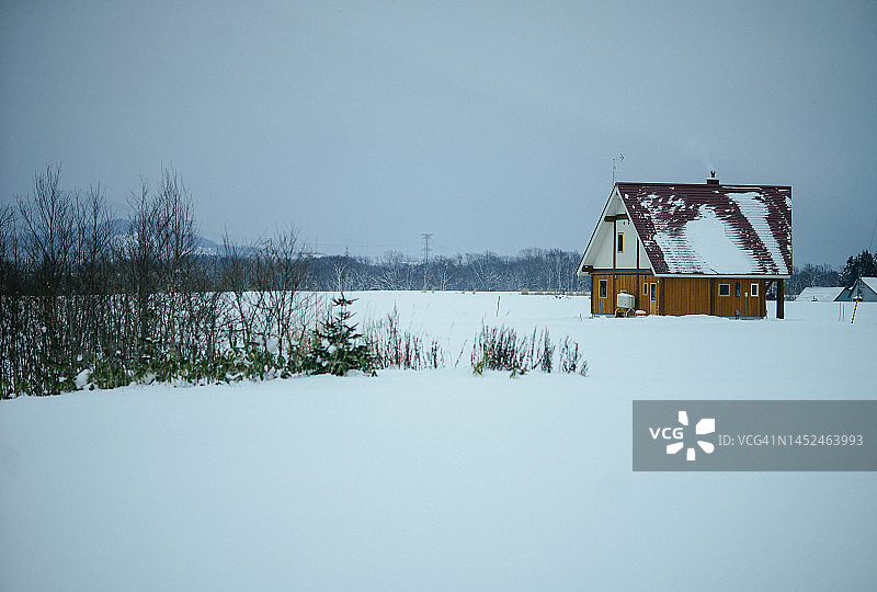 从札幌到新雪谷滑雪场的路上，雪覆盖了房屋和道路，靠近日本北海道的羊蹄山图片素材