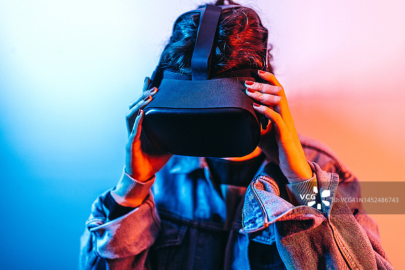 年轻时尚女人在霓虹灯工作室里戴着VR眼镜图片素材