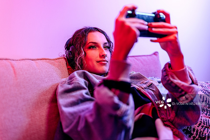 在公寓里玩手机网络游戏的年轻女人图片素材
