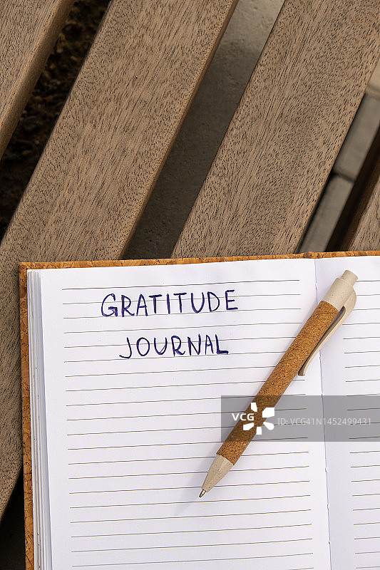 在木制长椅上写感恩日记。今天我感恩。自我发现日记、自我反思创意写作、自我成长个人发展概念。健康的精神健康，保持正念，整体健康实践图片素材