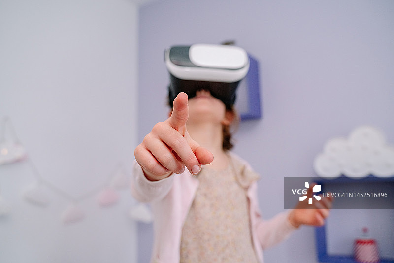小女孩在卧室里戴着VR眼镜指点特写图片素材