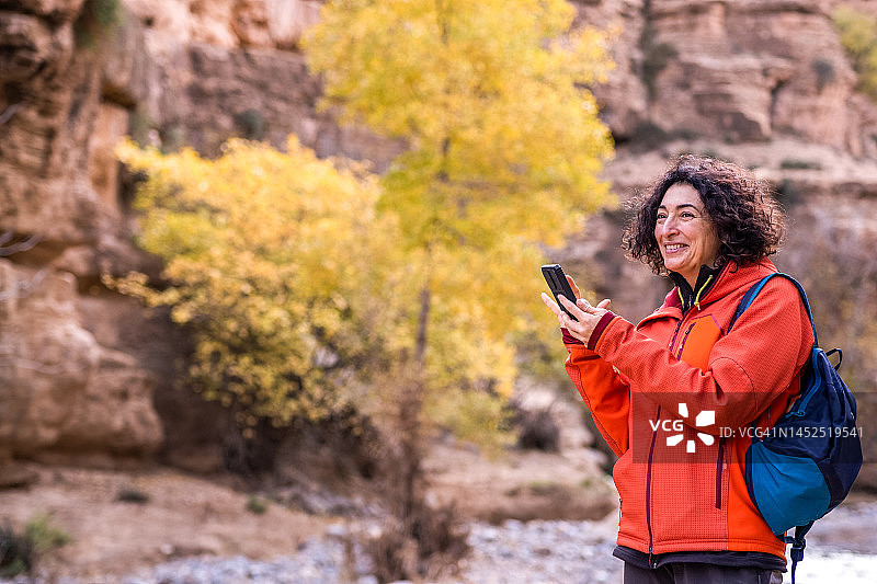 独自旅行的女人在山区穿红夹克使用手机图片素材