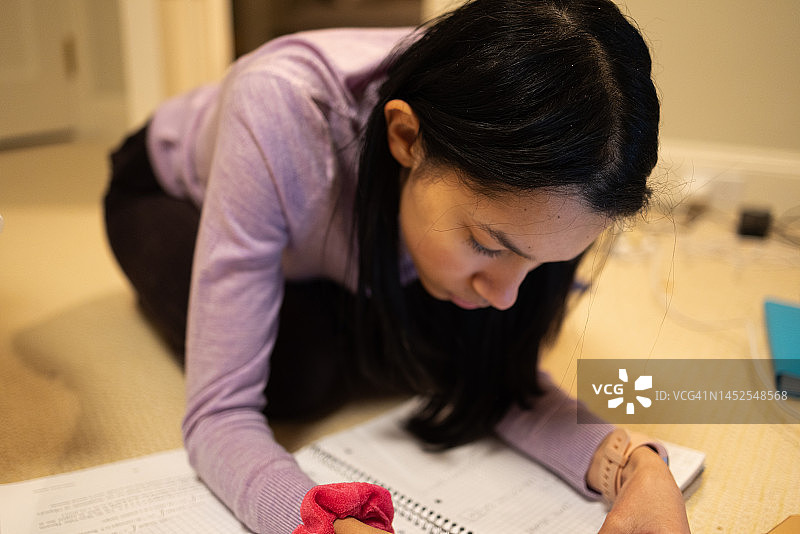 混血少女在卧室地板上做作业图片素材