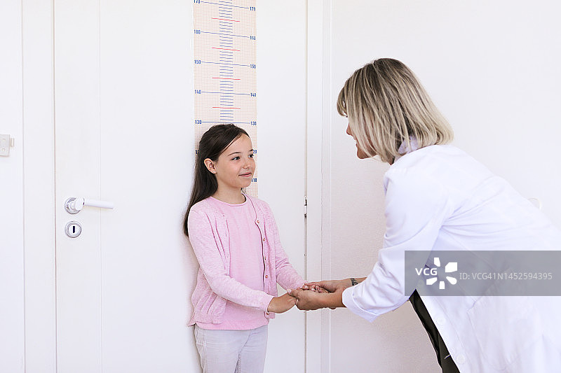 女营养师医生在她的医疗办公室测量一个小男孩的身高和体重图片素材