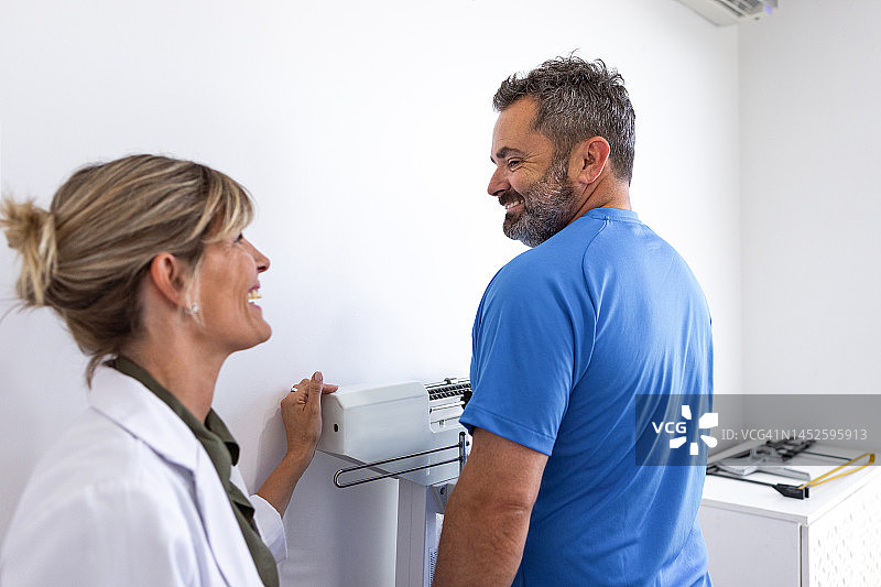 女营养师在办公室为超重男病人测量体重图片素材