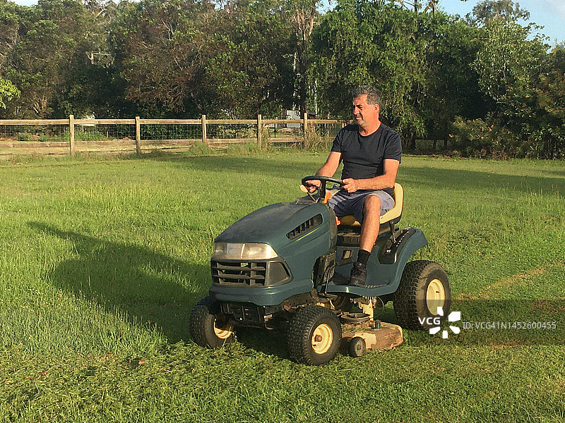 男人驾驶骑乘式割草机图片素材