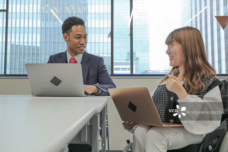 坐在轮椅上在办公室工作的女人图片素材