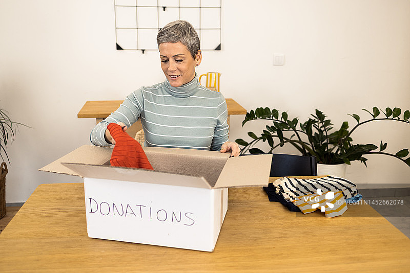 快乐的女人准备一箱衣服捐赠图片素材