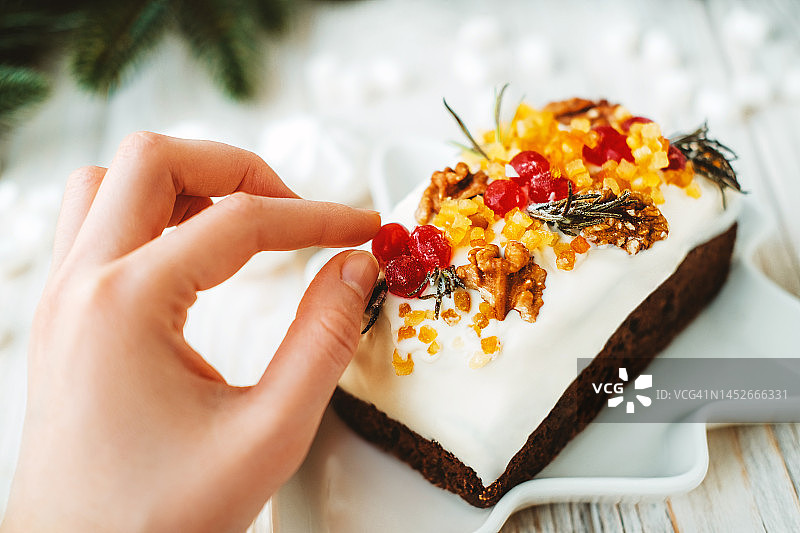 女人触摸圣诞蛋糕上的浆果图片素材