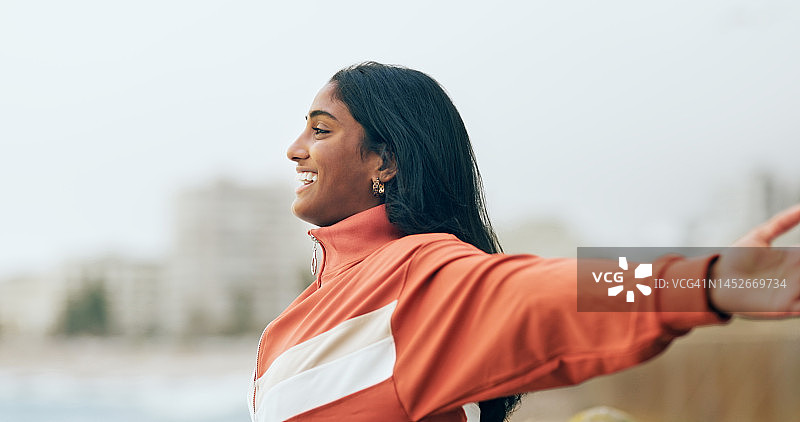 快乐的印度妇女在户外伸展双臂，感受海风，呼吸新鲜空气，充满目标、幸福、动力、健康、和平与希望，在自然中微笑、乐观和追逐梦想，获得成功图片素材