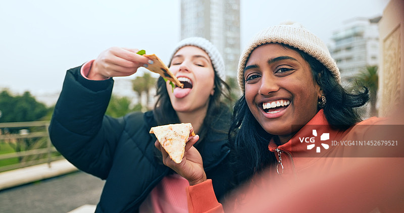 城市里一起吃披萨自拍的快乐女性朋友图片素材
