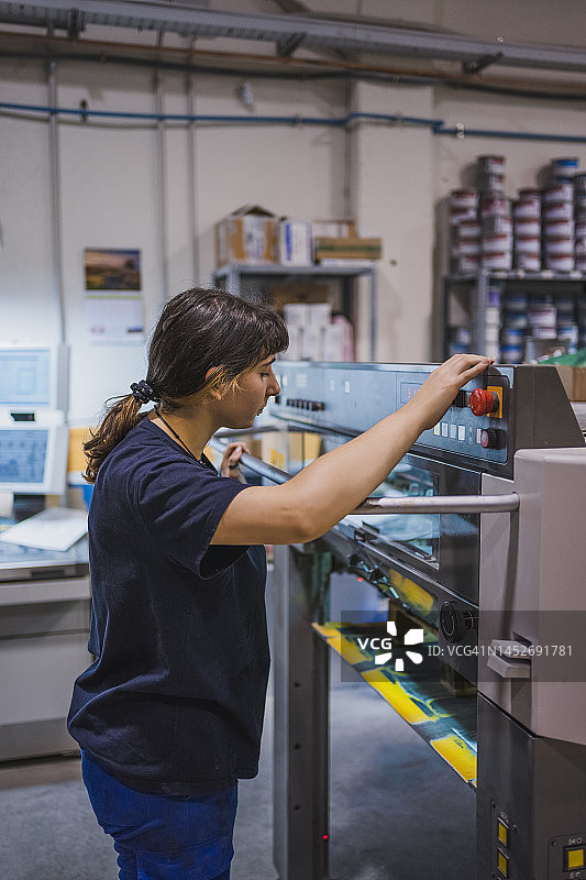 年轻女子在胶印机上控制印刷过程图片素材