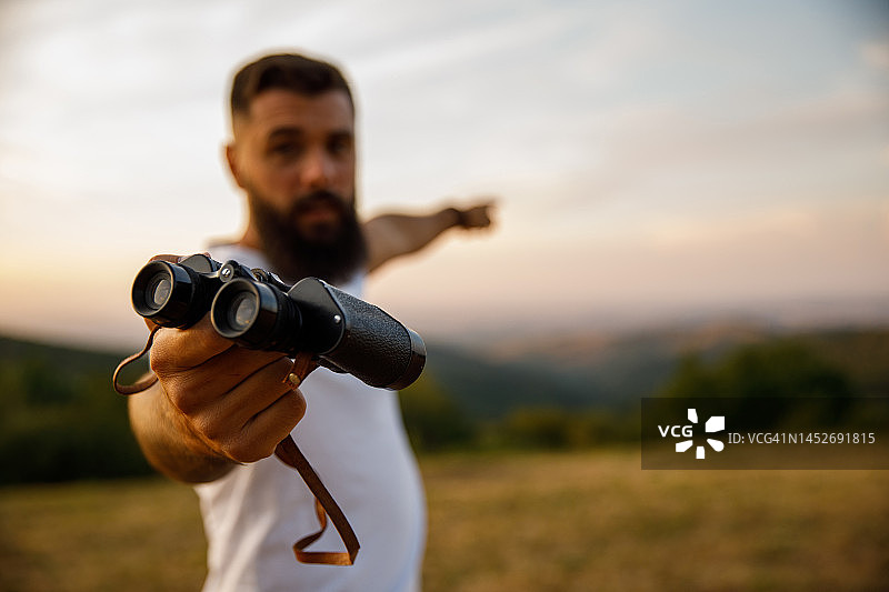 男人给你望远镜并指向远方图片素材